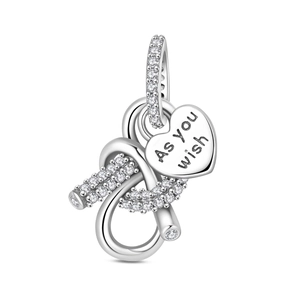 Close-up of silver infinity heart charm with white zircons and 'As you wish' engraving