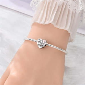Dettaglio macro di un ciondolo a cuore argentato con incisione familiare su bracciale