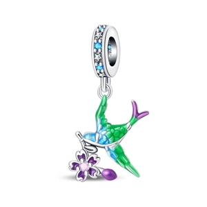 Macro detail of bird charm with green enamel and purple flower for DIY bracelets