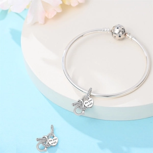 Macro detail of silver charm bracelet featuring diamond infinity and heart tag
