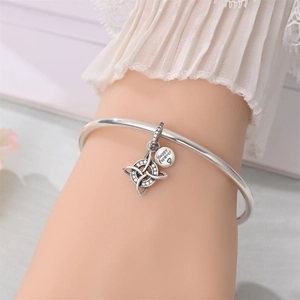 Close-up of silver bangle with Celtic knot charm and Happy Forever engraved heart tag
