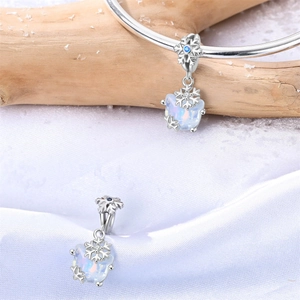 Detalle de un dije de copo de nieve plateado con ópalo en una pulsera de invierno