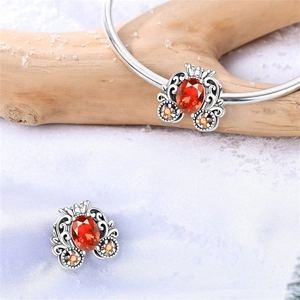 Vista macro de abalorios de carroza de calabaza plateados con piedras naranjas en pulsera