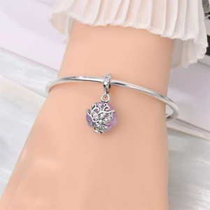 Silver bangle with purple gemstone charm and intricate engraving on female wrist