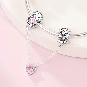 Detail of silver safety chain with cartoon boy and girl charms and pink heart crystal