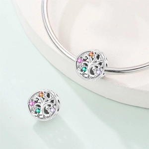 Detailed macro view of silver tree of life charm with colorful zircons and Familia engraving