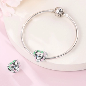 Detail of silver heart charms with enamel elephant icons and star-patterned bracelet