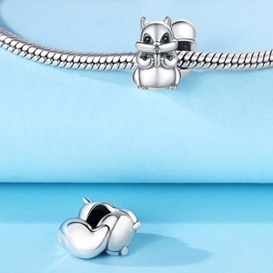 Macro shot of a silver squirrel charm with black enamel eyes on a snake chain bracelet