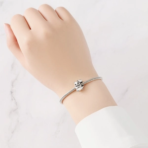Close-up of a silver squirrel charm on a snake chain bracelet worn on a woman's wrist