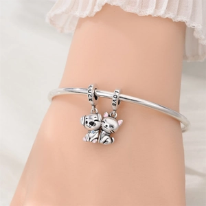 Detail of silver bracelet featuring cat and dog charms with Luck and Love engravings