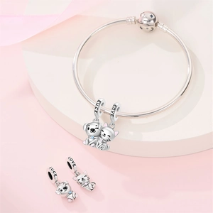 Macro shot of silver cat and dog charms with Luck and Love engravings on a bracelet