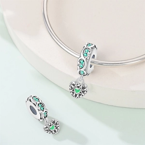 Nahaufnahme eines silbernen Herzanhängers mit grünen Zirkonia auf einem Armband