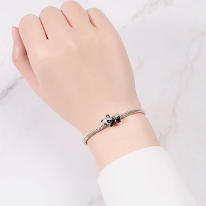 Wrist-worn silver snake chain bracelet featuring a detailed black and white panda charm