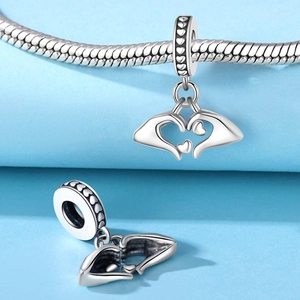 Makro-Detail des silbernen Herz-Charms mit umschlingenden Händen am Schlangenarmband