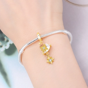 Macro shot of silver snake chain bracelet with golden star heart pendant detail
