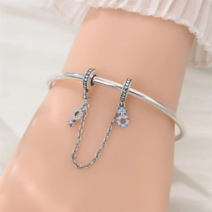 Detail of silver heart charms with pink and blue zircons on a beaded charm bracelet