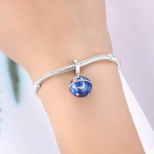 Detail of silver snake chain bracelet with blue enamel moon and star charm on wrist