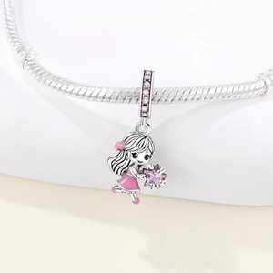Detail of silver girl charm with pink dress and star on a snake chain bracelet