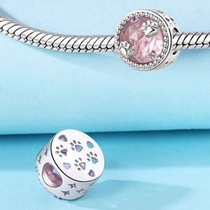 Macro di charm a zampa in argento con gemma rosa e dettagli a cuore su catena serpente