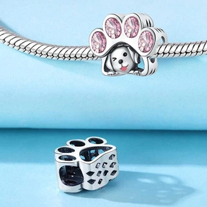 Dettaglio macro dello charm zampa di cane con cristalli rosa e viso di cucciolo in argento