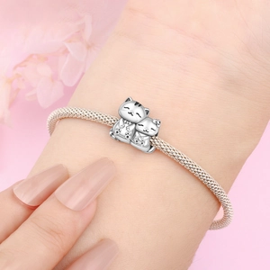 Dettaglio di bracciale intrecciato argento con ciondolo a forma di gatto e gattino