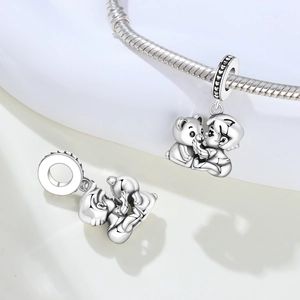 Detailed close-up of a silver boy hugging a teddy bear charm with heart embossed ring