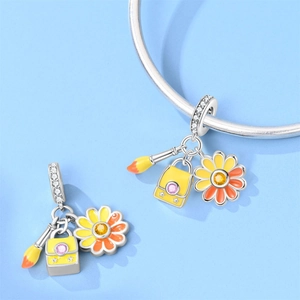 Detail of travel charms with enamel paintbrush, backpack, and daisy on a silver clasp