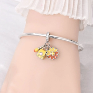 Silver charm bracelet featuring colorful enamel schoolbag and daisy pendants on wrist