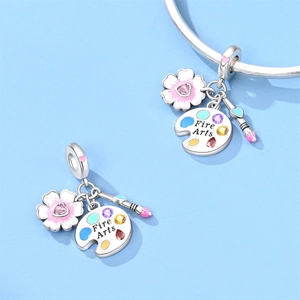 Macro view of silver charm with pink flower, Fire Arts palette, and paintbrush detail