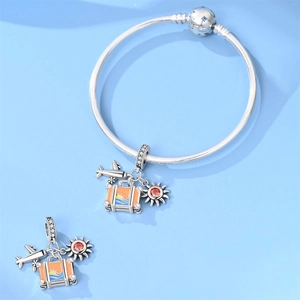 Detail of travel charm set with airplane, suitcase and sun pendant on silver bracelet
