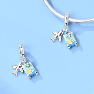 Detail of silver travel charms featuring miniature airplanes and tropical enamel pendants