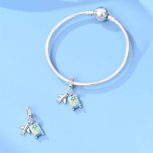 Detailed view of silver-plated travel charms featuring a plane and blue enamel suitcase