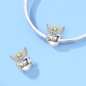 Macro shot of silver heart angel charm with Wish engraving and gold hair details