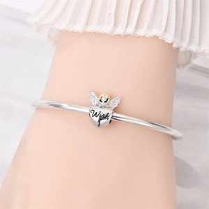 Detailed macro view of silver bangle with angel wings heart charm and Wish engraving
