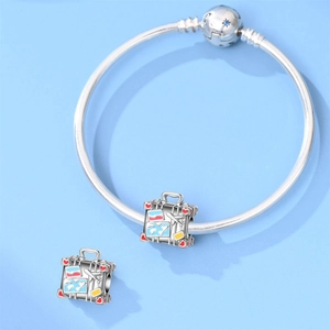 Detail of travel-themed charms on snake chain bracelet with suitcase and world map