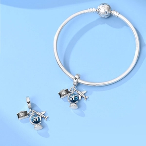 Macro detail of silver airplane and camera charms on a snake chain travel bracelet