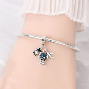 Silver travel charm bracelet with miniature camera, globe and airplane on white background