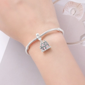 Bracelet serpent argenté avec charm maison en émail rose détaillé sur le poignet