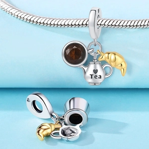 Close-up of silver tea pot, gemstone cup and golden croissant charms on snake chain