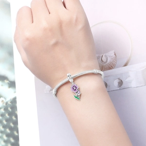 Detail of silver snake chain bracelet featuring a purple enamel iris flower charm