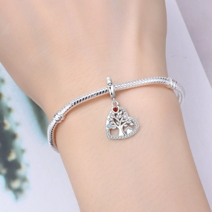 Gros plan détaillé d'un bracelet à breloques argenté avec un pendentif cœur Arbre de Vie