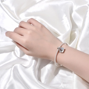 Detailed view of silver woven bracelet with a camera charm engraved with COFFEE text