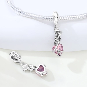 Macro shot of silver rose pendant with pink heart-shaped crystal on a snake chain