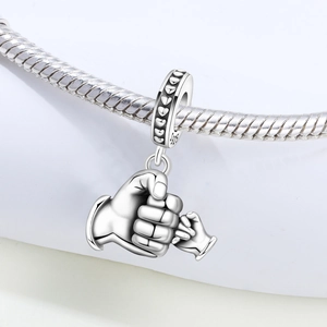 Vue macro d'un charm en argent S925 avec design de mains jointes sur chaîne serpent