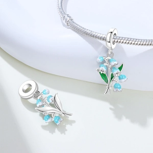 Macro detail of lily of the valley flower charm pendant with blue enamel and silver plating