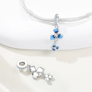 Macro shot of silver iris flower charm with blue enamel petals and sparkling zircons