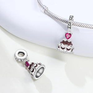 Close-up of a three-tier cake charm with a red heart zircon on a silver snake chain