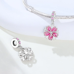 Macro detail of cherry blossom charm with pink enamel and sparkling zircon on silver chain