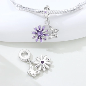 Macro detail of purple daisy flower charm and butterfly pendant with cubic zirconia