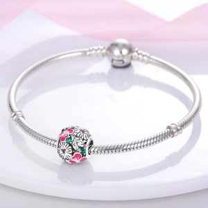 Primer plano detallado de la pulsera de plata con un dije floral de esmalte rosado